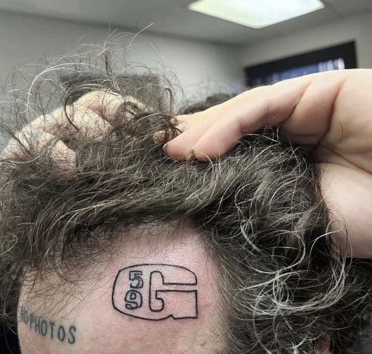 a close up of a person with a tattoo on his head and hair in the background