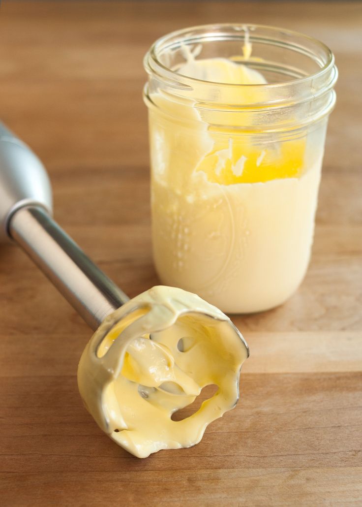 a glass jar filled with yellow liquid next to a pastry mixer on top of a wooden table