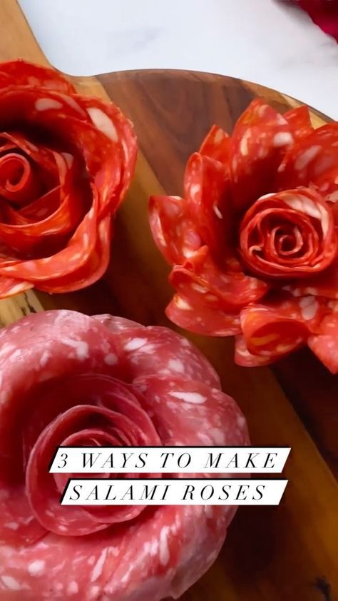 two red flowers sitting on top of a wooden cutting board next to a piece of meat