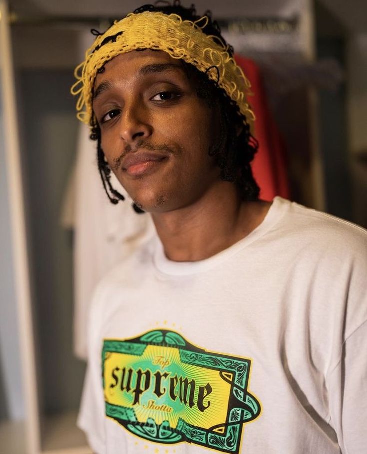 a young man with dreadlocks and a supreme t - shirt in the closet