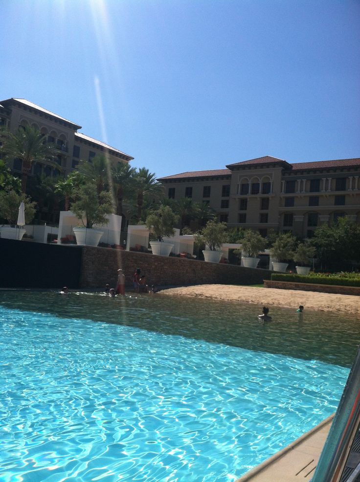 people are swimming in the blue water near an apartment complex