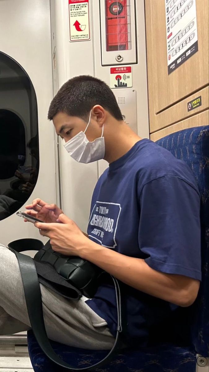 a man wearing a face mask while looking at his cell phone