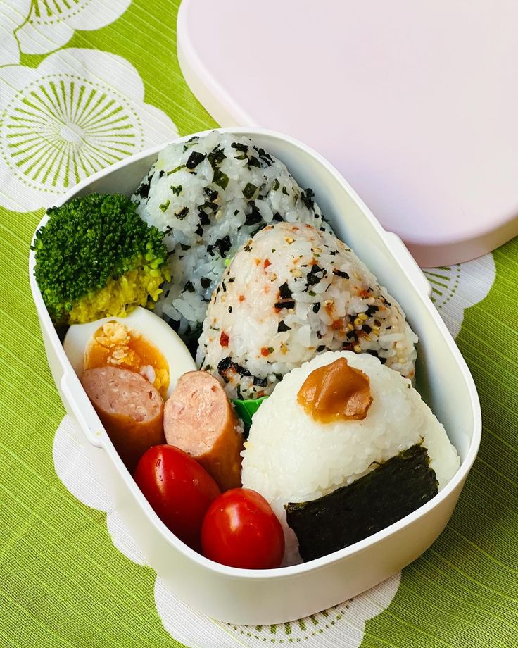 a bento box filled with rice, meat and veggies on a table