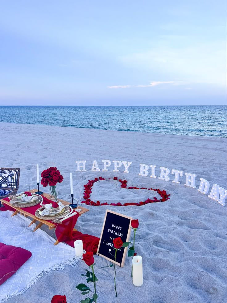 a happy birthday sign on the beach with roses