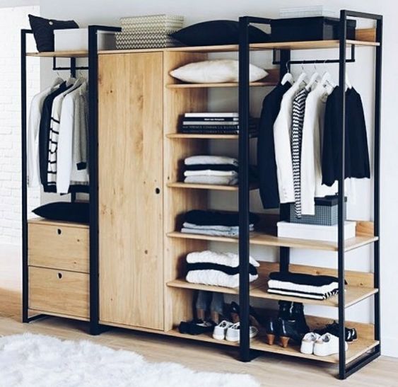 an open wardrobe with clothes and shoes on it in a room next to a window