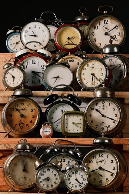 many clocks are stacked on top of each other in different colors and sizes, all with the same time