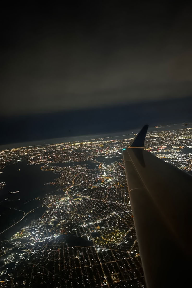 an airplane wing flying over the city lights at night