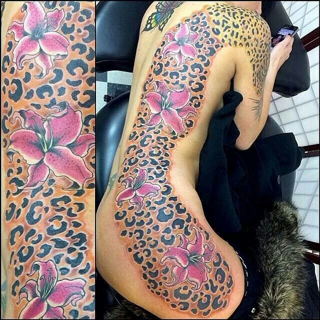 the back of a woman's body covered in leopard print and pink flower tattoos