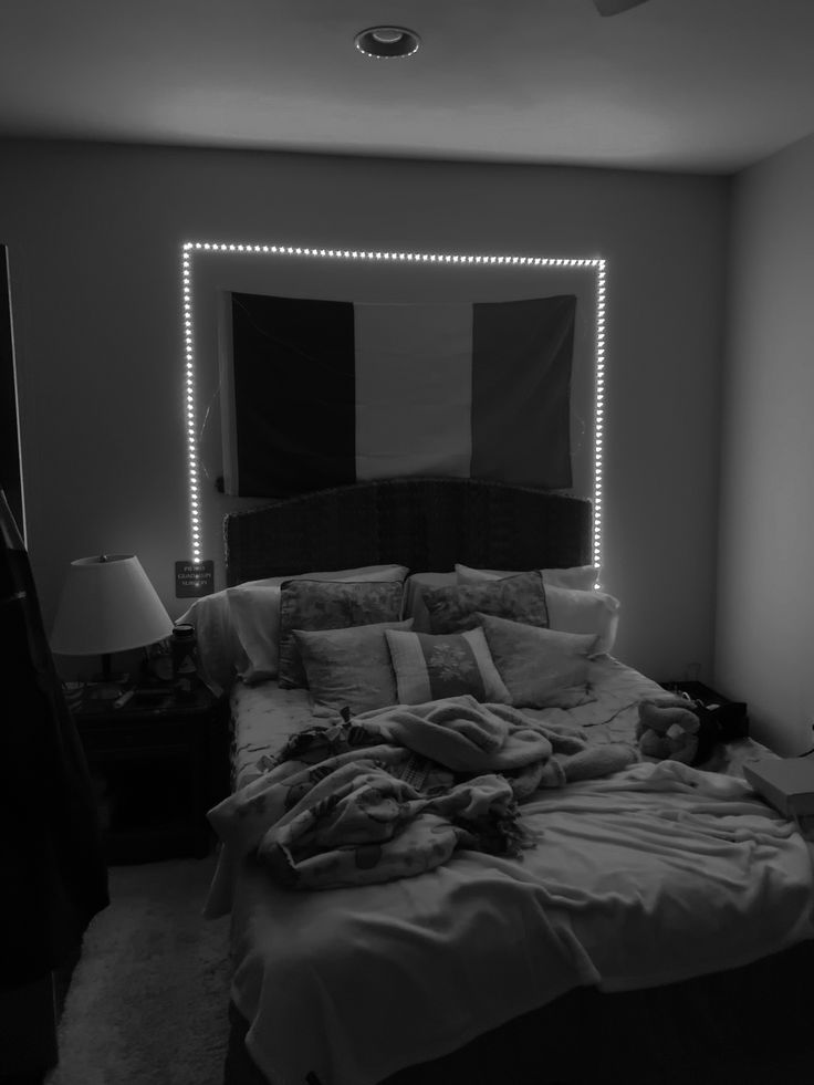 black and white photograph of a bed in a bedroom with lights on the headboard