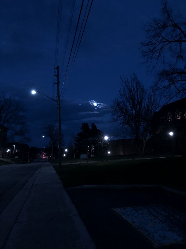 an empty street at night with the moon in the sky