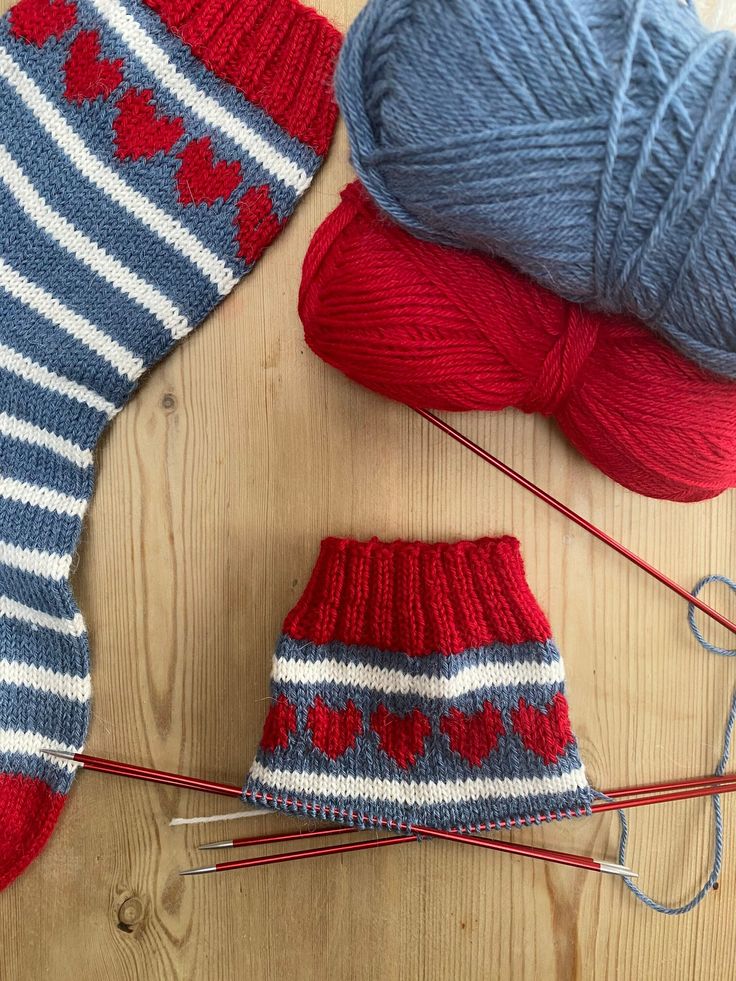 two knitted mittens and yarn on a wooden surface