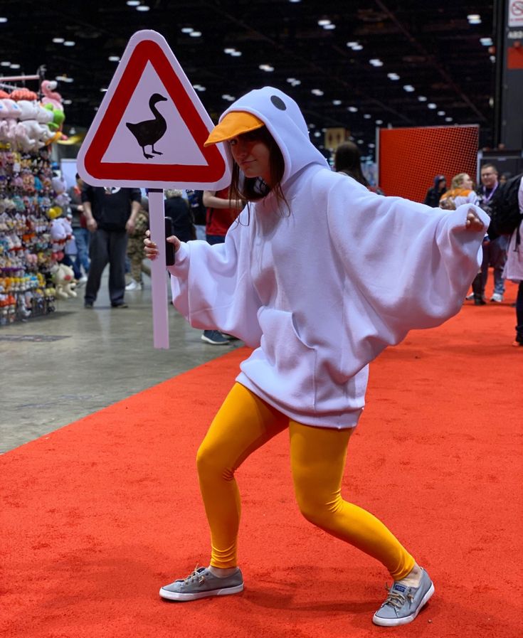 a person in a duck costume standing next to a sign