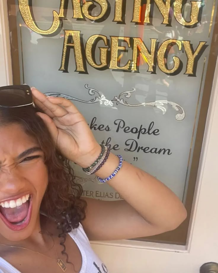 a woman holding her hair in front of a sign that says casting agency on it