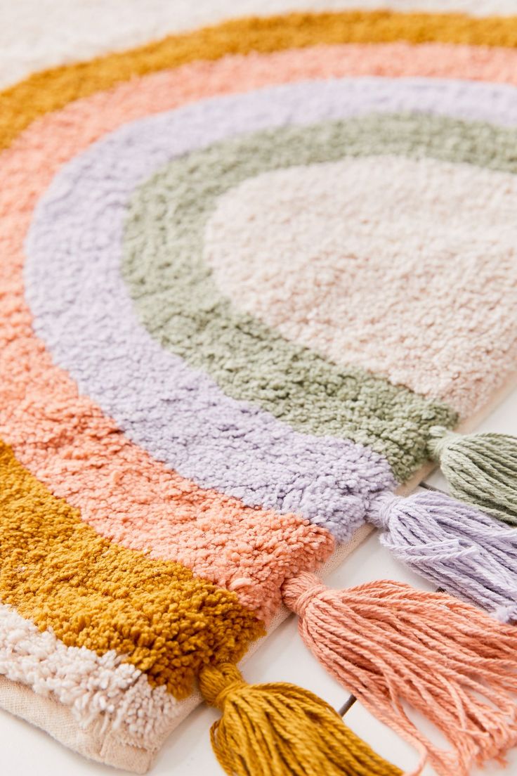 a multicolored rug with tassels laying on the floor next to it