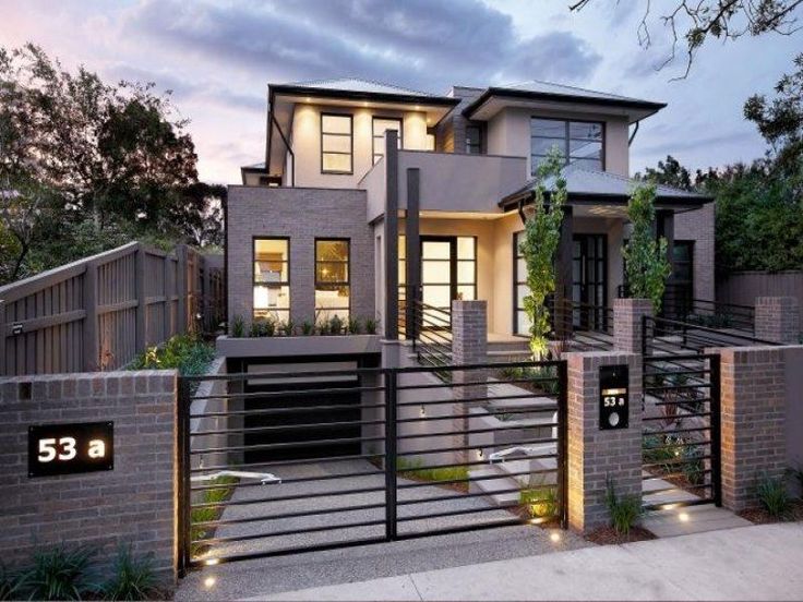 a modern house is shown at dusk with its lights on and the front gate lit up