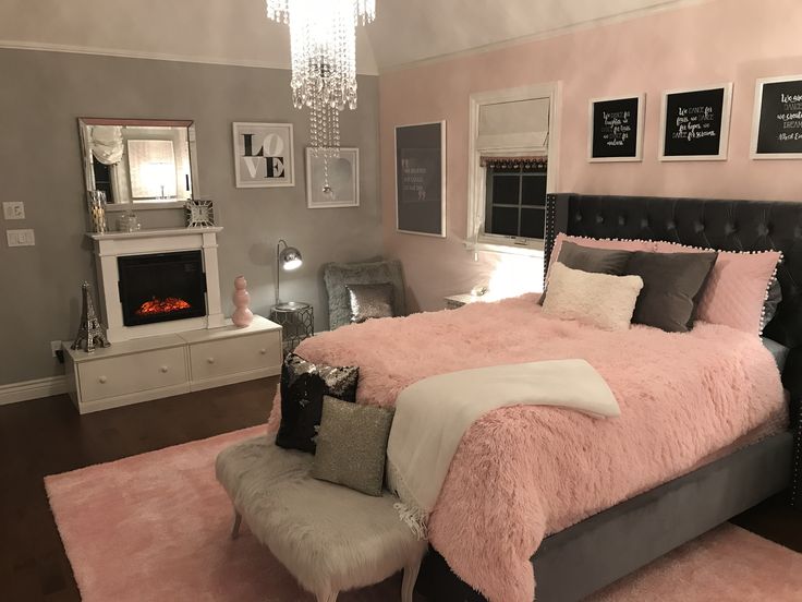 a bedroom decorated in pink and grey with a bed that has a fluffy blanket on it