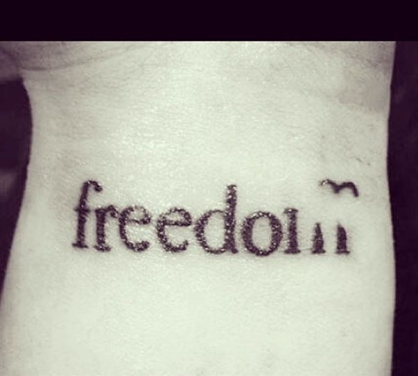 a black and white photo of a person's wrist with the word freedom written on it