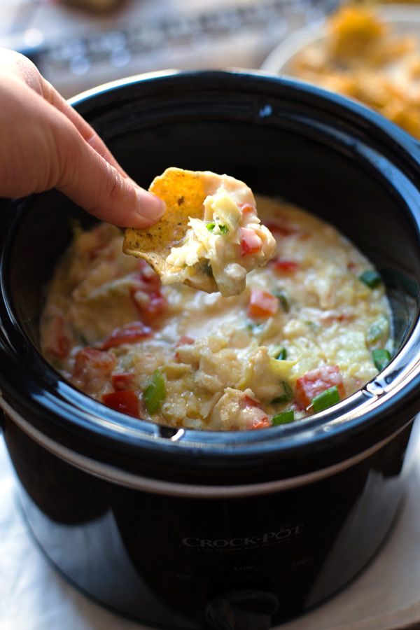 a person dipping some food into a crock pot