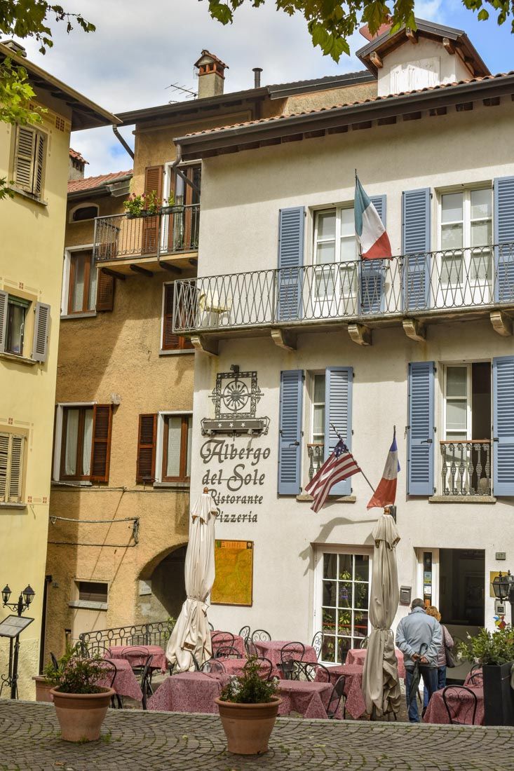 the building has blue shutters on it's windows and people are standing outside