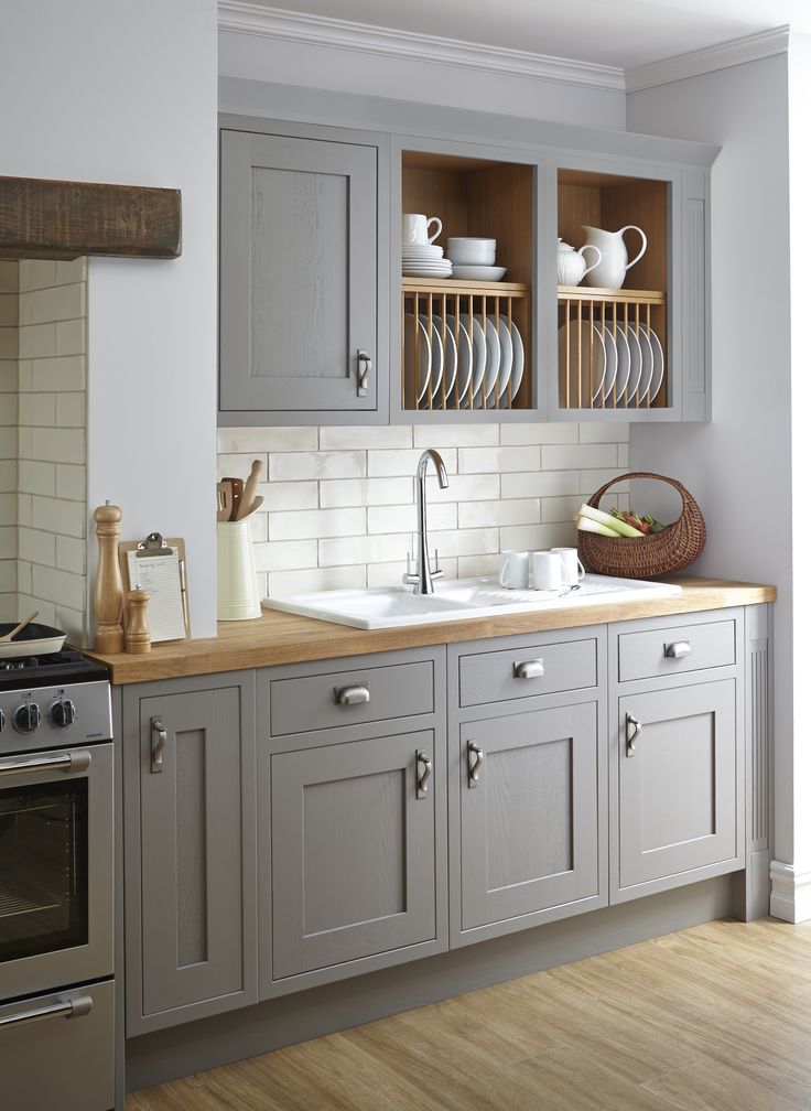 a kitchen with gray cabinets and wooden floors