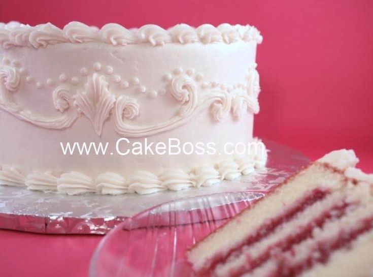 a white cake sitting on top of a table next to a slice of cake