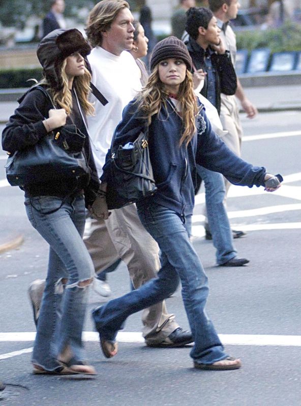 several people walking down the street with one person talking on a cell phone and another standing behind them