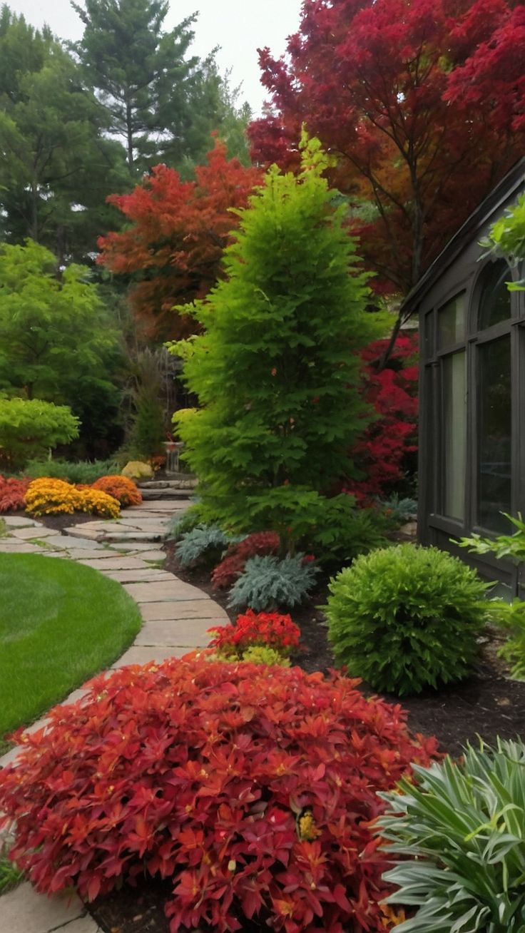 a garden filled with lots of different types of trees and shrubs in front of a house