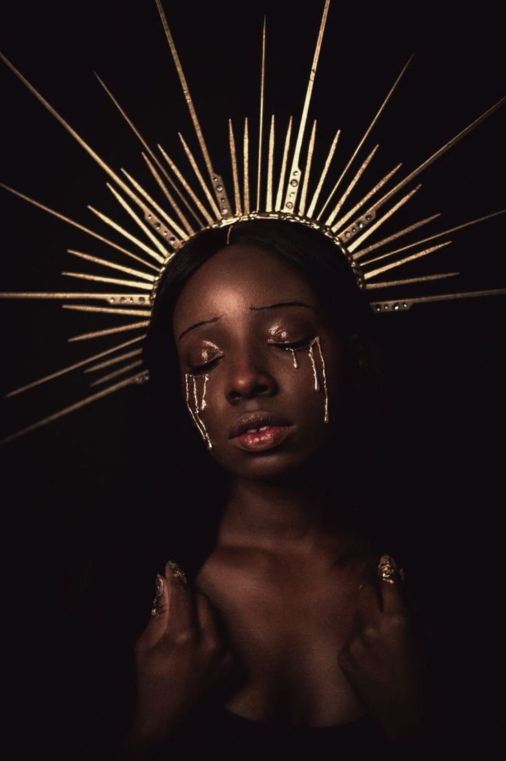 a woman with makeup on her face standing in front of a sun - shaped object