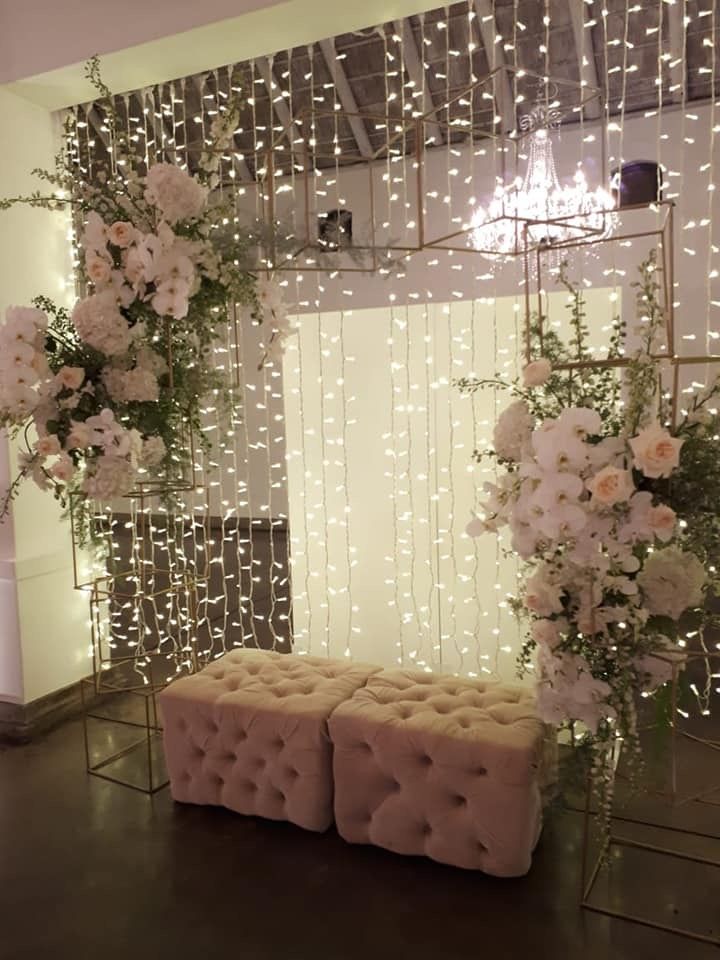 a room with flowers and lights on the wall, two benches are in front of it