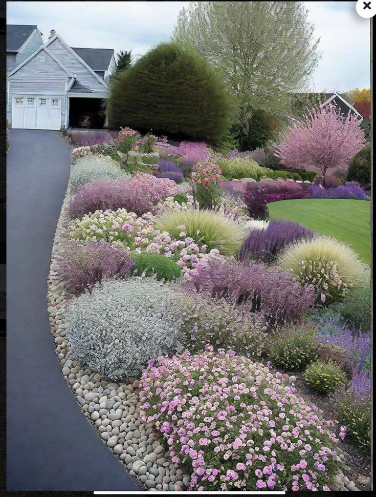 a garden with lots of different types of flowers and plants in it, along side a house