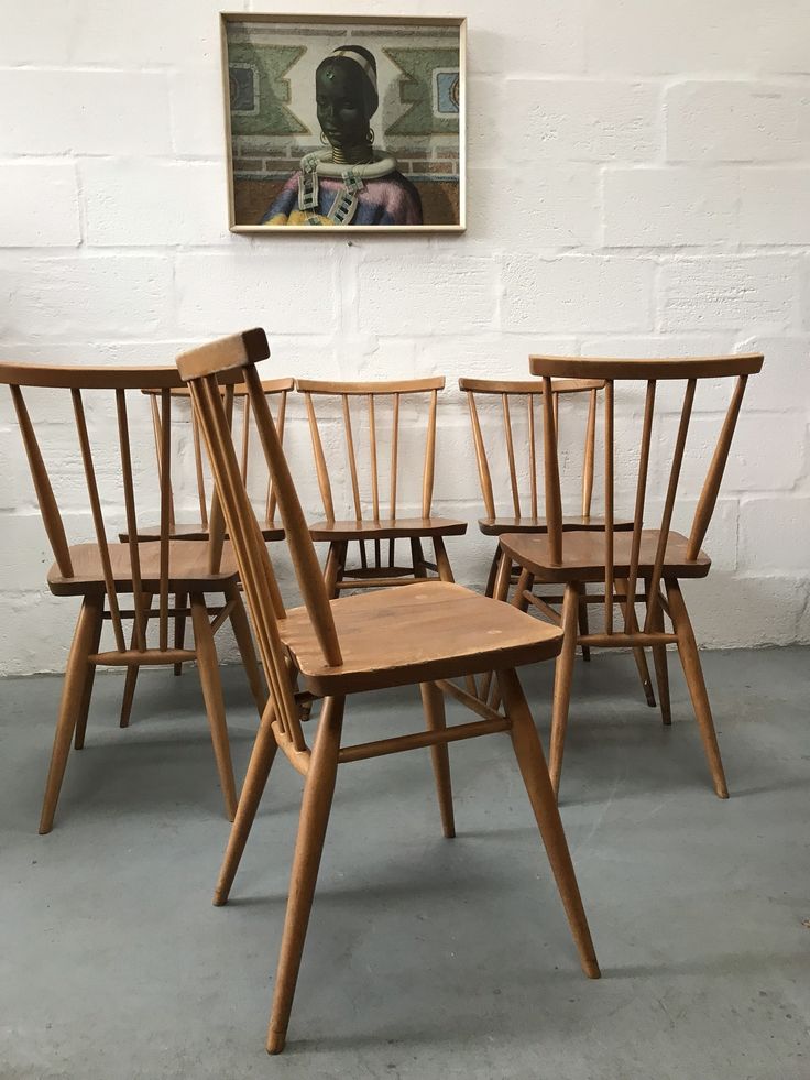 six wooden chairs sitting in front of a white brick wall