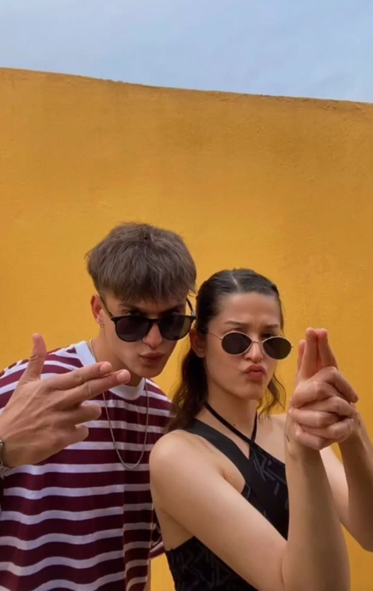 a man and woman standing next to each other with their fingers up in the air