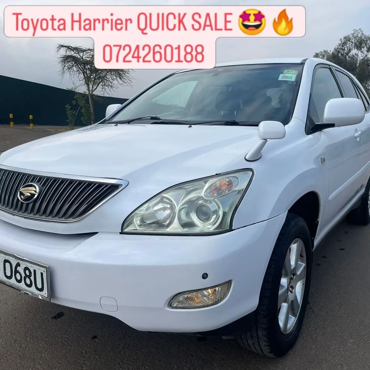 a white car parked in a parking lot next to a sign that says toyota harrier quick sale