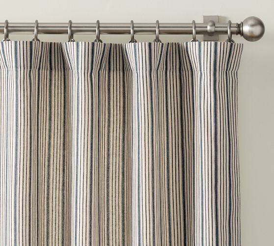 a striped curtain hanging on the side of a window with metal rod ends and an eyelet