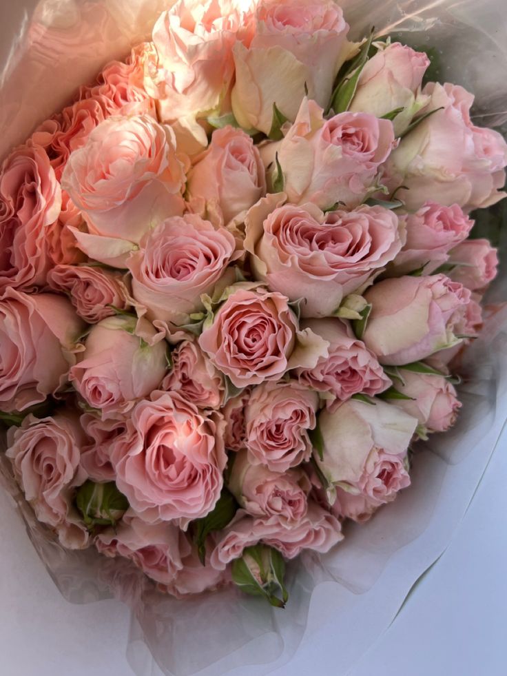 a bouquet of pink roses is wrapped in white paper and ready to be used as a bridal