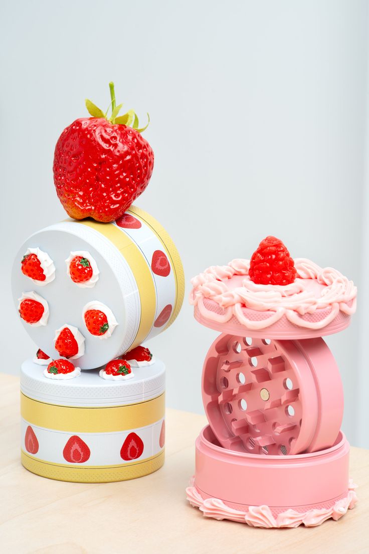 two strawberry shaped boxes sitting on top of each other, one with a strawberry on it's top