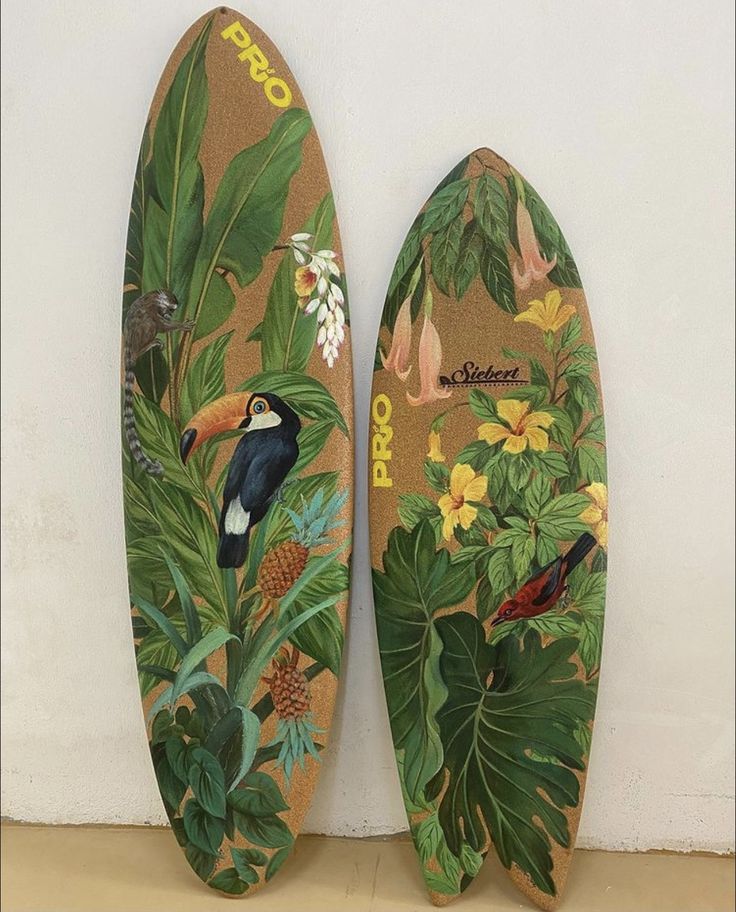 two surfboards are decorated with tropical plants and birds