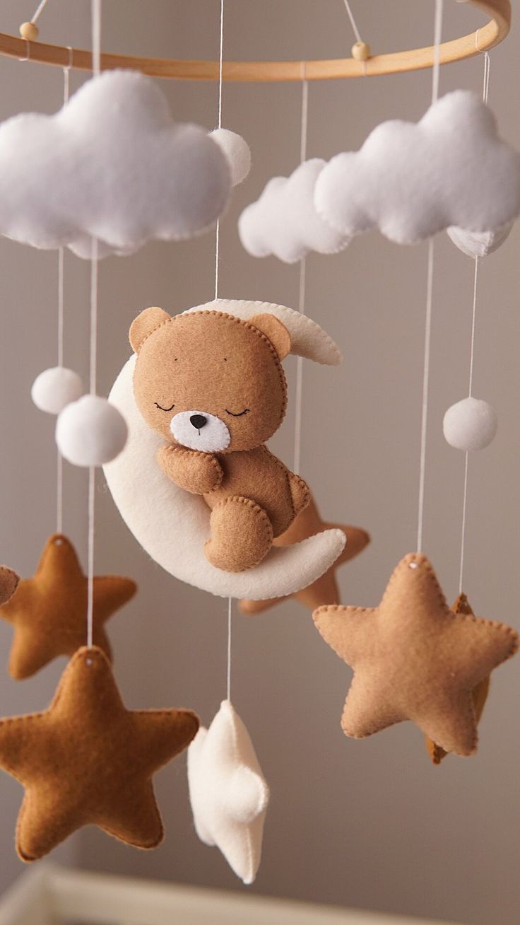 a teddy bear is sleeping on the moon and stars hanging from it's strings