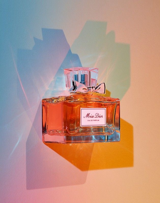 a bottle of perfume sitting on top of a colorful wall next to a light fixture