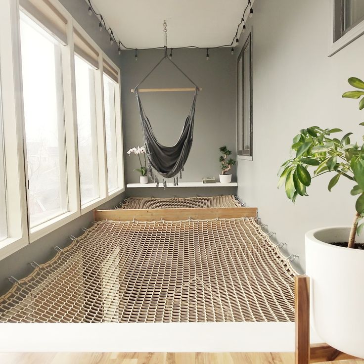 a hammock hanging in the middle of a room next to a potted plant