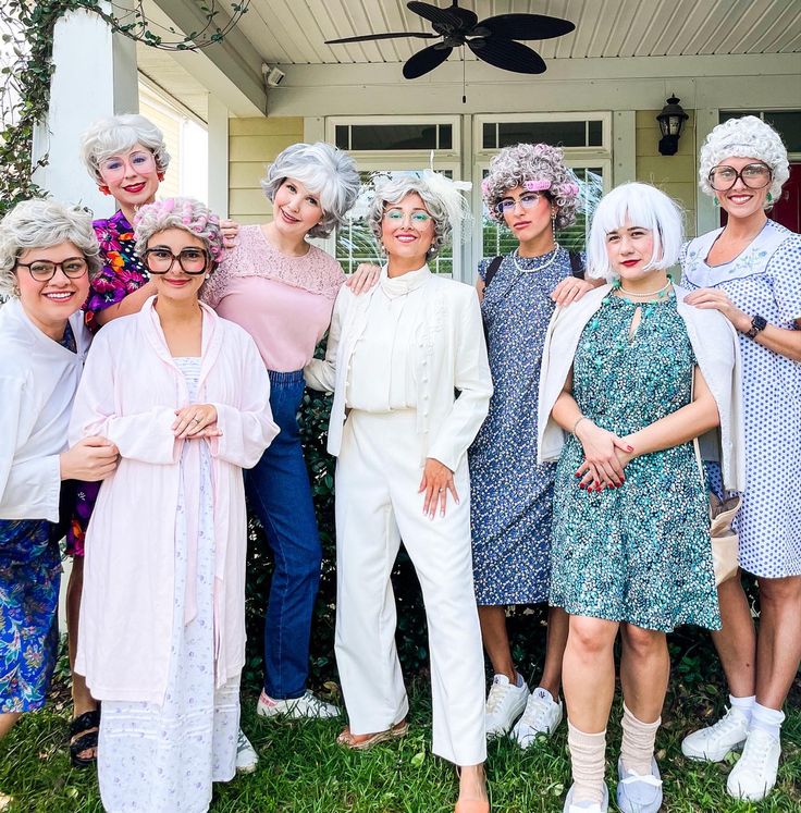 a group of women standing next to each other in front of a house