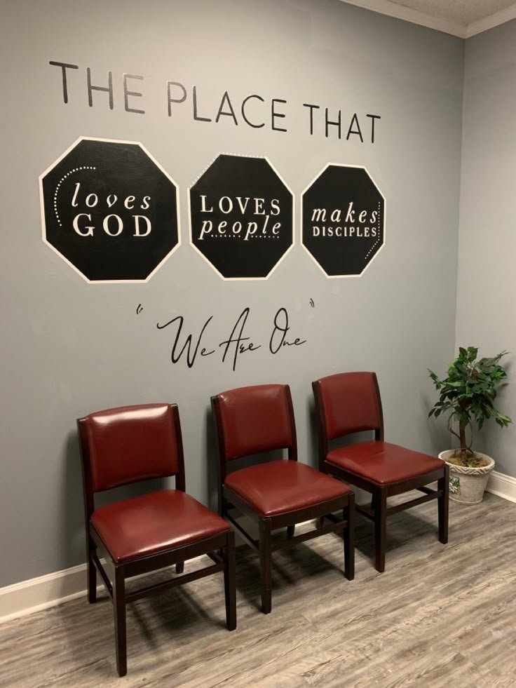 three red chairs sitting in front of a wall that says the place that loves people