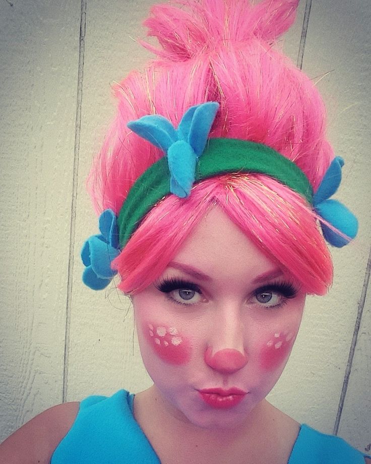 a woman with pink hair and blue eyes has her face painted like a cat's head