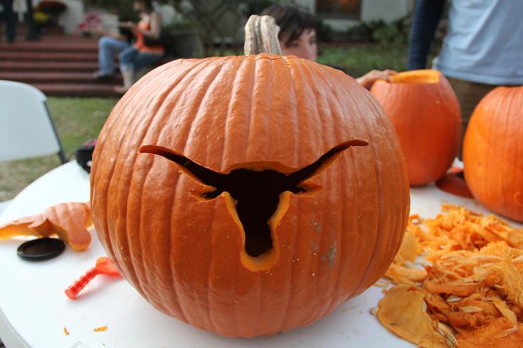 a pumpkin that has been carved to look like a texas longhorn with an evil face on it