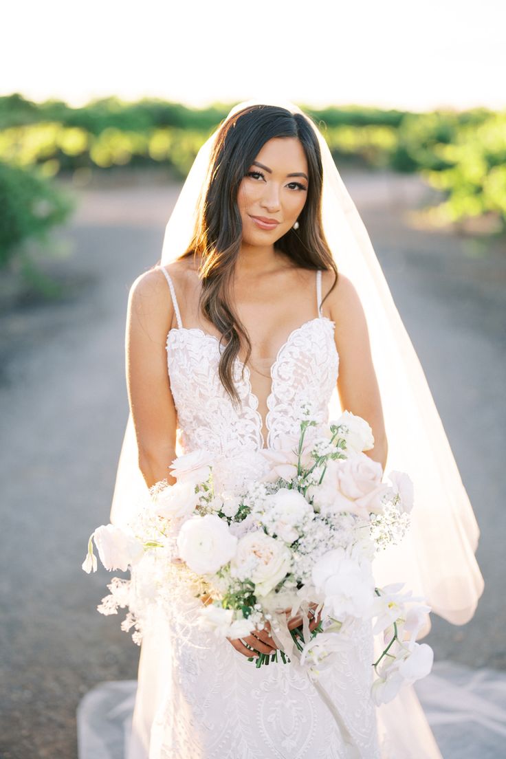 a woman in a wedding dress holding a bouquet and posing for the camera with her veil over her head