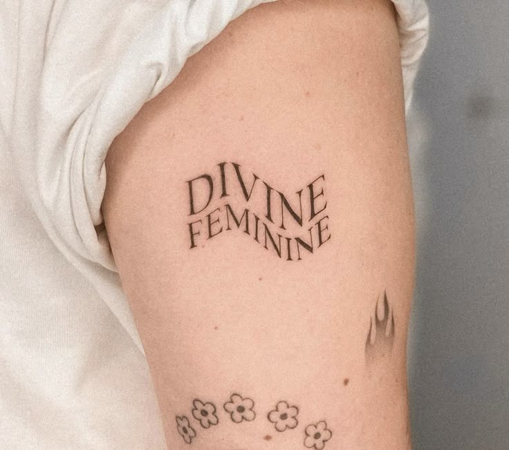 a close up of a person's arm with a tattoo that reads divine feminine