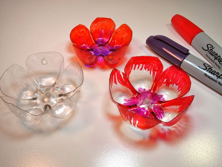 three glass vases with flowers in them and two markers on the table next to them