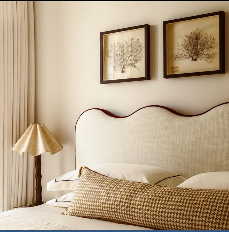 two framed pictures hang on the wall above a bed with white linens and pillows