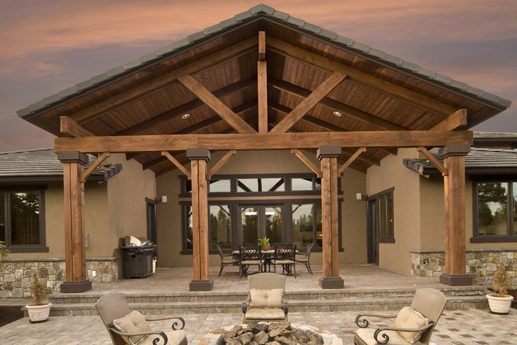 an outdoor living area with chairs, tables and fire pit in front of a house