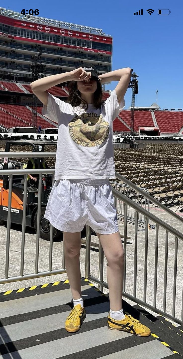 a woman is standing on the steps in front of an empty stadium with her hands behind her head